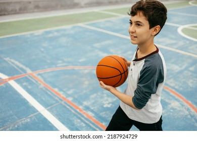 12 Year Old Boy Playing Basketball. Teenager Training Basketball Outdoors.