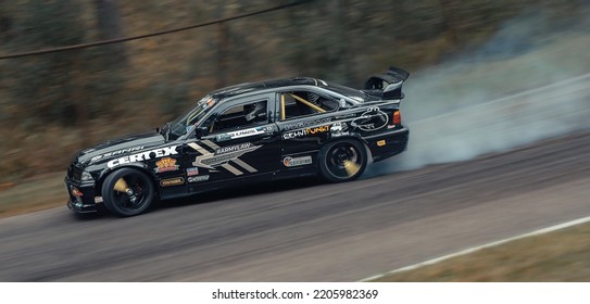 12-05-2022 Riga, Latvia. A Car On The Track Blowing Smoke From Its Exhaust Pipes, A Modified Car Is Turning Down A Road.