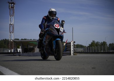 12-09-2022 Riga, Latvia A Person Riding A Motorcycle On A Race Track, A Man Riding A Motorcycle On A Road With A Dog.