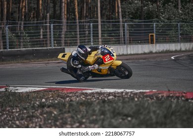 12-09-2022 Riga, Latvia A Person Riding A Red Motorcycle On A Track, Man On Red Racing Bike Moving Fast Down The Race Track.