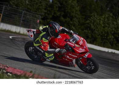 12-09-2022 Riga, Latvia A Person Riding A Red Motorcycle On A Track, Man On Red Racing Bike Moving Fast Down The Race Track.