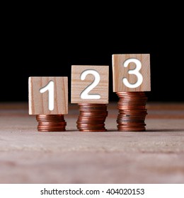 123 Number With Wooden Block On Stacked Coins