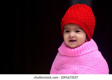 13 Months Old Indian Baby Girl Wearing Red Winter Cap And Pink Poncho
