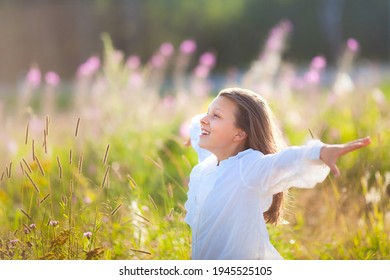 13 Year Old Girl Stands On Blooming Field In Summer Time And Enjoys Clean Air And Freedom. Child Holds Arms Wide Open Like She Is Flying.