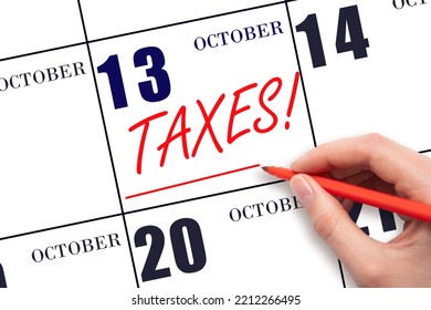 13th day of October. Hand drawing red line and writing the text Taxes on calendar date October 13. Remind date of tax payment. Tax day concept. Autumn month, day of the year concept.