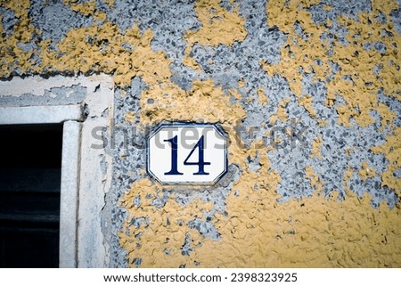 14, house number fourteen on blue and yellow peeling wall