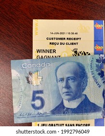 14 June 2021, Brampton, Ontario - Canada . Winning OLG Lottery Ticket With 5 Dollar Bill On A Hard Surface.