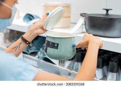 14 June 2021, Ufa, Russia: Woman Housewife In Protective Mask During The Covid Pandemic Shopping For Cooking Pot In IKEA Market