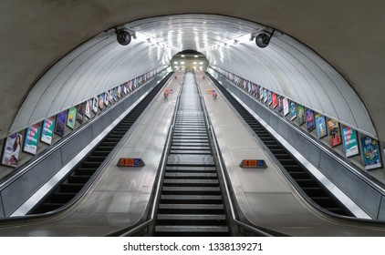 14 March 2019 - London, United Kingdom. Symmetrical View Of Long Escalators Leading Out Of The London Underground Tube Station. Exterion Media Advertising Panels On The Sides. 