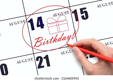 14th day of August. The hand circles the date on the calendar 14 August, draws a gift box and writes the text Birthday. Holiday. Summer month, day of the year concept.