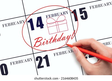 14th day of February. The hand circles the date on the calendar 14 February, draws a gift box and writes the text Birthday. Holiday. Winter month, day of the year concept.