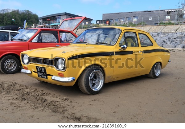 14th May 2022- A sporty 1969 Ford Escort\
Mexico, two door saloon car,  in a public parking area on Pendine\
Sands in Carmarthenshire, Wales,\
UK.