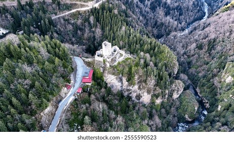 A 14th-century castle nestled between mountains, surrounded by lush greenery. The castle, known as Zil Kale, is an ancient fortress with a rich history, offering a scenic view of the natural landscape - Powered by Shutterstock