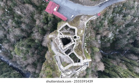 A 14th-century castle nestled between mountains, surrounded by lush greenery. The castle, known as Zil Kale, is an ancient fortress with a rich history, offering a scenic view of the natural landscape - Powered by Shutterstock