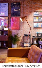 15 December 2020, St. Petersburg Russia. Vinyl Record Store Interior With Posters On Brick Wall, Brown Leather Couch, Armchair, Houseplants, Lamp. Cozy Room Loft Design.