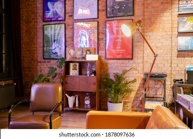 15 December 2020, St. Petersburg Russia. Vinyl Record Store Interior With Posters On Brick Wall, Brown Leather Couch, Armchair, Houseplants, Lamp. Cozy Room Loft Design.