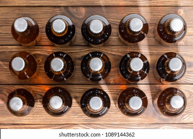 15 Neatly Aligned Rows Of Bottled Craft Beer Capped With Bottle Tops Viewed Top Down On A Wooden Table