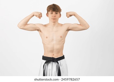 A 15 year old Shirtless Karate Black Belt Boy, Wearing Gi Trousers Flexing His Arms - Powered by Shutterstock