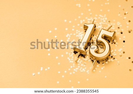 15 years celebration festive background made with golden candle in the form of number Fifteen lying on sparkles. Universal holiday banner with copy space.