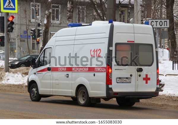 15-02-2020\
Syktyvkar, Russia. A red and white ambulance with blue flashing\
lights rides along a city street in\
winter.