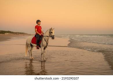 15-year-old rider rides his white horse on the seashore - Shutterstock ID 2193290107