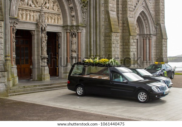 16 March 2018 A hearse and a funeral car parked\
outside St Colman\'s Cathedral in Cobh Cork Ireland during a service\
for a local dignitary