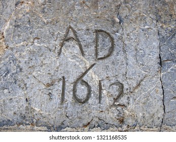 1612 AD Isolated Inscription Carved On Stone. 17th Century Inscription On Old Building, Cracked Wall, Listing An Exact Year Number Of The Kingdom Of France In The Early Modern Period. Rural Occitanie