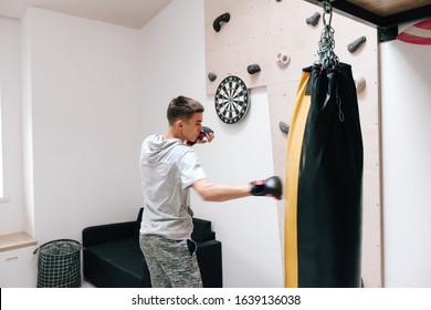 16-17 Years Old Teenage Boy Workout With Boxing Bag In Home Gym Room. Young Teen Male Having Hobby To Be Strong And Sportish Man.