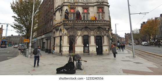 16th November 2018 Dublin. Busker In Between D'olier Street And Westmoreland Street, In Front Of The Irish Waxworks Building With Both Halloween And Christmas Symbols On The Window Ledge. 