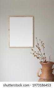 16x20 thin wood picture frame mockup with large terra cotta vase and tree branches as a prop.