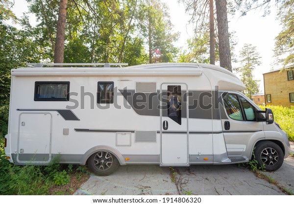 17 july 2020, Russia, Novosibirsk: A white mobile\
home is parked in the woods. Caravan for life and family road\
travel. No people.
