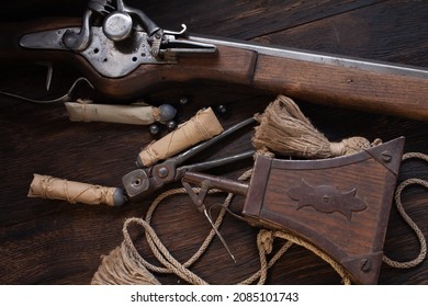 17th century ancient flintlock musket with powder flask and led bullets on wooden deck.