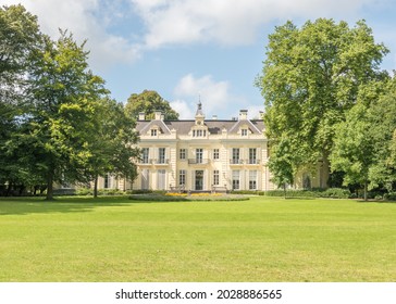 17th century monumental mansion with a lawn, trees and blue sky with white clouds