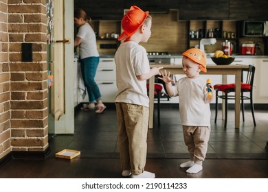 18.11.2018 Vinnitsa, Ukraine: Two Little Brothers Playing At Home, Running Around The Kitchen, Helping Mom With Cooking, Playing Home Games