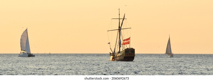 18th century sailing yacht and modern sailboats in an open sea at sunset. Holland. Old tall ship. Recreation, vacations, cruise, historical reenactment, past, history, regatta, transportation