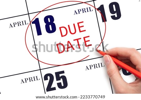 18th day of April. Hand writing text DUE DATE on calendar date April 18 and circling it. Payment due date. Business concept. Spring month, day of the year concept.