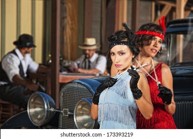 1920s flapper women near car and men in hats