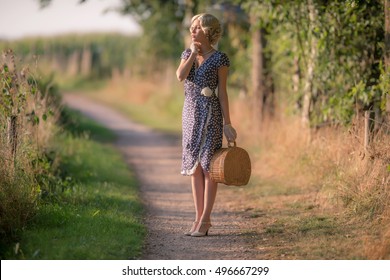 1920s Retro Fashion Woman Standing With Handbag On Rural Pathway.