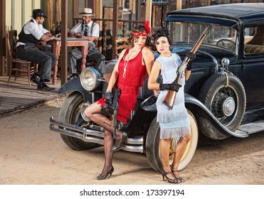 1920s vintage gangster women holding weapons near car
