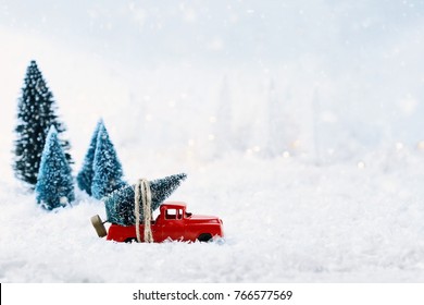 1950's antique vintage red truck hauling a Christmas tree home through a snowy winter wonder land. Extreme shallow depth of field with selective focus on vehicle.