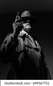 1950s Style Detective Posing In The Dark, He Is Holding A Weapon And Wearing A Fedora Hat, Noir Film Character