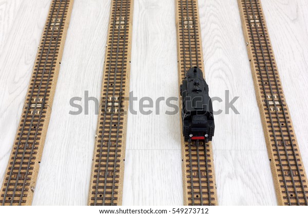 1950s vintage model steam locomotive on the rails\
over a wooden texture\
floor