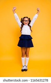 1-september and back to school concept. Full length, legs, body, size vertical portrait of crazy small girl in skirt stand isolated on vivid yellow background raising her fists, hands up