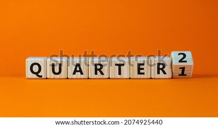 From 1st to 2nd quarter symbol. Turned a wooden cube and changed words 'quarter 1' to 'quarter 2'. Beautiful orange table, orange background. Business, happy 2nd quarter concept, copy space.