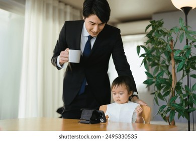 A 1-year-old child watching a video on his smartphone and his father wearing a suit before going to work - Powered by Shutterstock