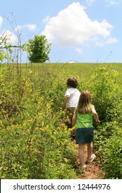 2 children on a trail walking up a small hill