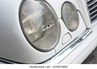 2 Circular Headlights Of A White Luxury Car. An RFID Sticker Placed On One Of The Lamps.