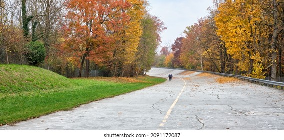 2 Cyclists In The Old Track With Parabolic Curve Of The Monza Circuit In Italy During Autumn On A Cloudy Day