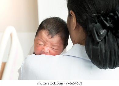 2 days old asian newborn baby crying on nurse's shoulder in hospital