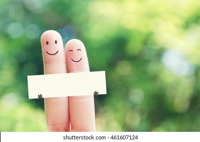 2 Fingers Holding Blank Paper While Smiling Face With Nature Bokeh Background. Paper Empty For Message And Wording.